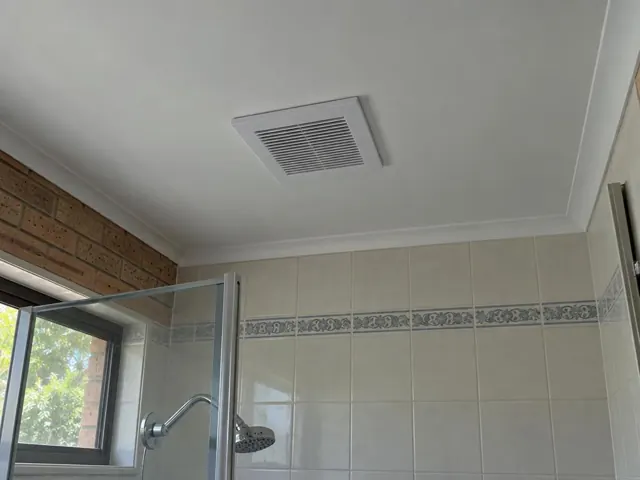 Ceiling exhaust fan above a tiled shower in a bathroom with brick and glass walls in Highland Park